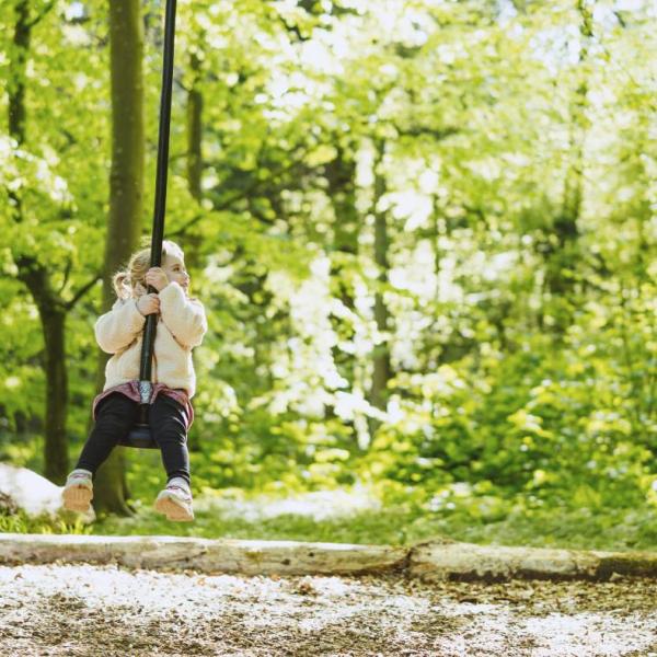 Pige på gynge på naturlegeplads